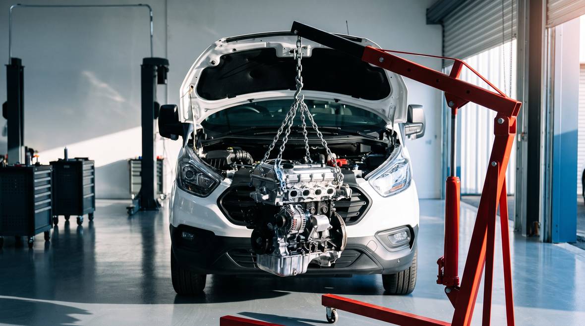 Reconditioned engine being lowered into a van engine bay